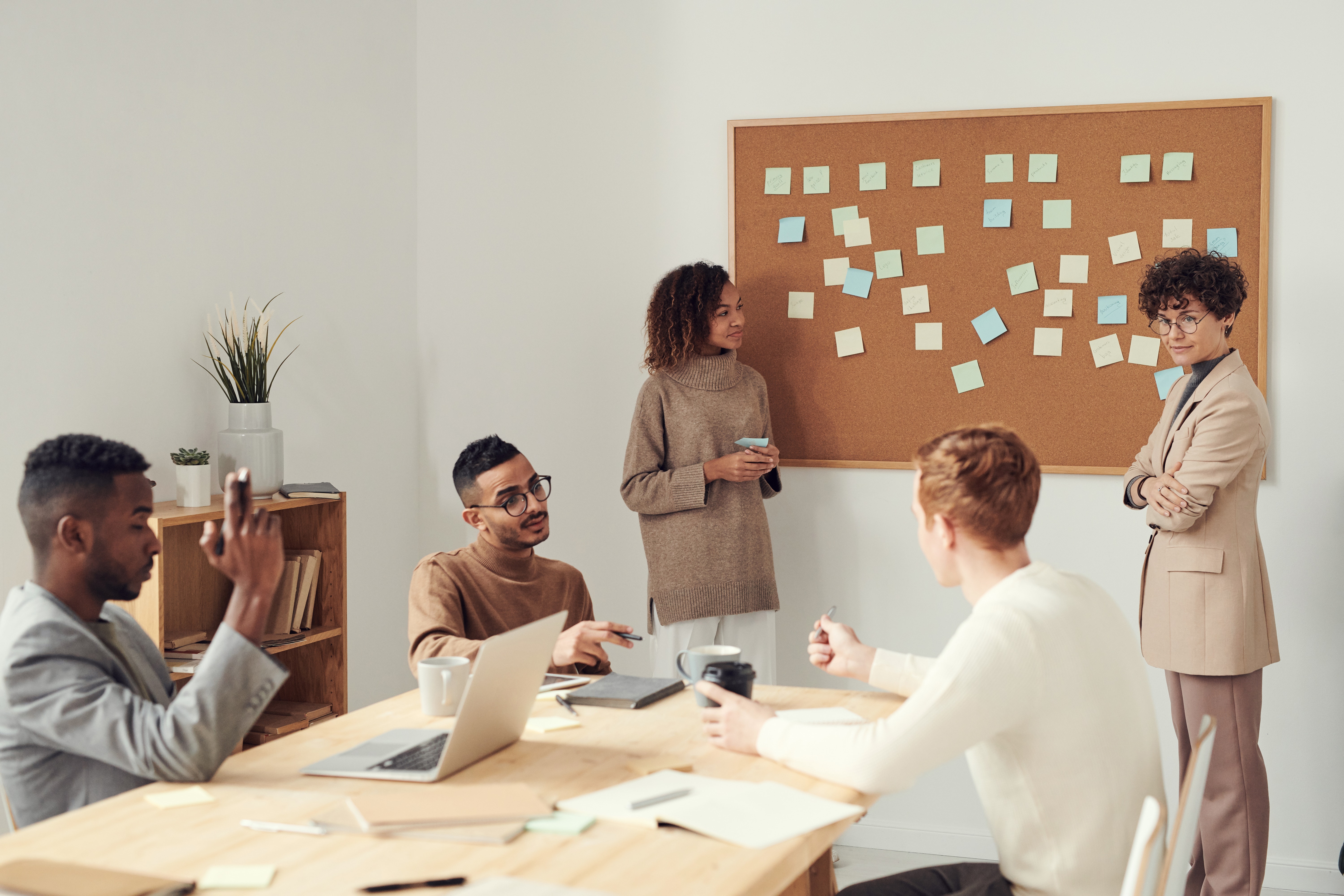 Menschen sitzen vor Pinnwand mit Post Its